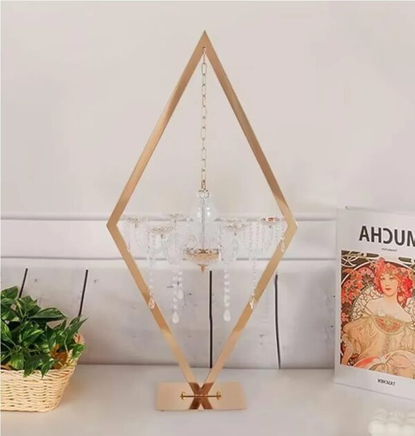 Rent elegant tabletop decor from Houston Party Rental Services, featuring a gold geometric diamond frame with a hanging crystal chandelier centerpiece. Perfect for weddings, corporate events, and upscale parties in Houston, TX. Available for rent with full-service setup, styling, and delivery.